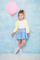 Full length. Cute little girl holding a pink balloon on a blue background.