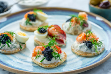 Selection of cocktail blinis with salmon, cured bresaola, crayfish, caviar, quail eggs and sour...