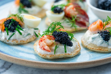Selection of cocktail blinis with salmon, cured bresaola, crayfish, caviar, quail eggs and sour...