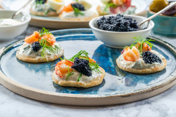 Selection of cocktail blinis with salmon, crayfish, caviar and sour cream - gourmet party food