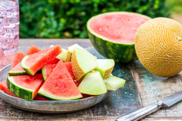 Slices of sweet, refreshing watermelon and honeydew melon on a garden table. Summer outdoor eating. © beataaldridge