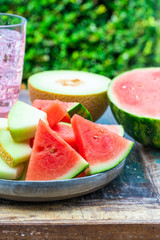 Slices of sweet, refreshing watermelon and honeydew melon on a garden table. Summer outdoor eating.