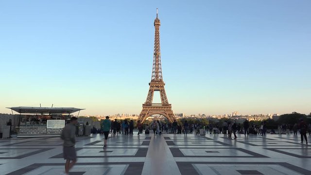 Eiffel tower on beautiful evening light, people passing on Trocadero