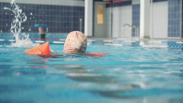 a little girl in inflatable armlets floats in the pool. Bracers for swimming. The girl learns to swim.