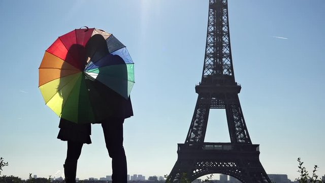Couple of lovers silhouettes with colored umbrella close to Eiffel tower in Paris