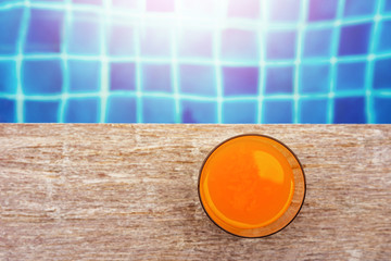 Summer Drink at the Swimming Pool. Glass of Orange Juice on the Poolside. Relaxation on Vacation or Holidays Concept. Top View