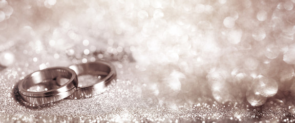 Wedding rings on festive silver background