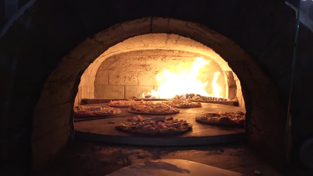 Shovel put pizza in wooden oven, flame burning fast