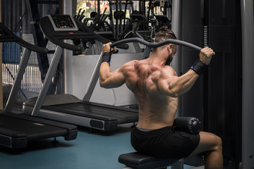 Fototapeta na wymiar Hombre fuerte con grandes músculos entrenando jalón en el gimnasio. Ponerse en forma.