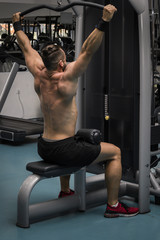 Fototapeta na wymiar Hombre fuerte con grandes músculos entrenando jalón en el gimnasio. Ponerse en forma.