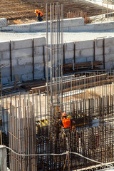 Construction of a large commercial building. Worker connects the armature at the construction site