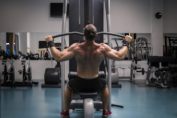 Fototapeta premium Hombre fuerte con grandes músculos entrenando jalón al pecho en el gimnasio. Ponerse en forma.