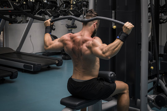 Hombre fuerte con grandes m&uacute;sculos entrenando jal&oacute;n en el gimnasio. Ponerse en forma.