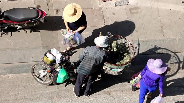 Man selling pineapple on street from a basket on bike. Saigon.