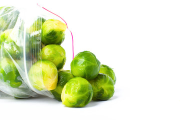 Plastic bag with frozen brussel sprouts isolated on white. Vegetable preservation