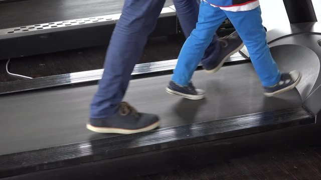 Parent feet walking together with child feet on running device, father feet walk near kid feet , increase child independence
