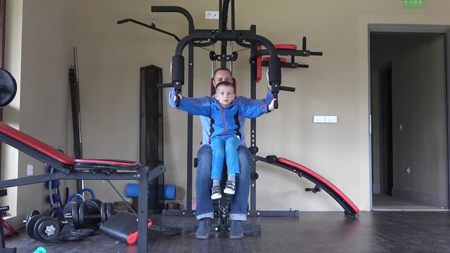 Young father and little son exercises on farce device at gym, healthy sport