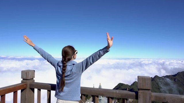 Woman raising hands, looking on landscape on Fansipan mountain in Sapa, Vietnam