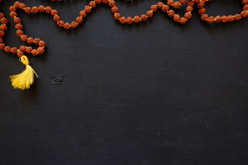 Tulasi beads on a black background. Beads of 108 (one hundred and eight) beads on a wooden board. Rosary for reading mantras. - obrazy, fototapety, plakaty