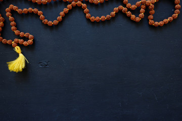 Tulasi beads on a black background. Beads of 108 (one hundred and eight) beads on a wooden board.