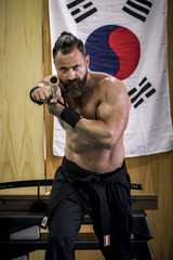 Hombre fuerte con grandes músculos entrenando artes marciales con arma han bo. Defensa personal...