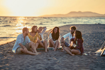 Smiling friends with guitar at beach. friends relaxing on sand at beach with guitar and singing.