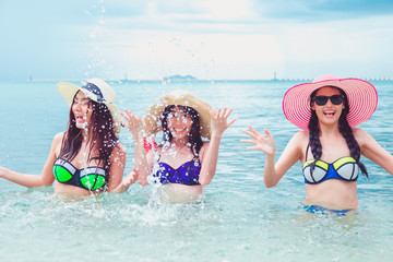 Three beautiful bikini young asian best friends having fun and splashing water.