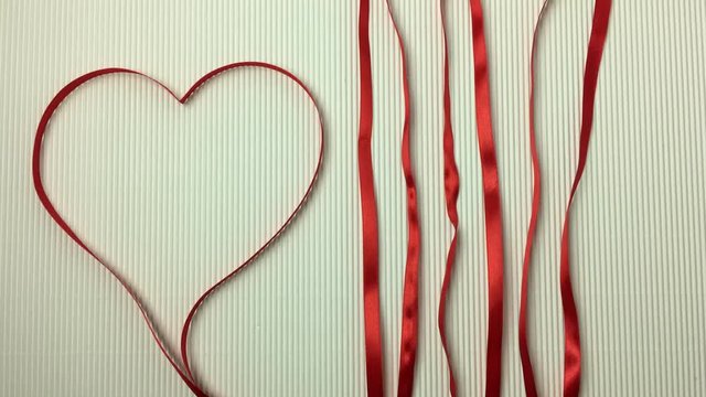 Corazon rojo junto a cintas formando lineas van callendo.