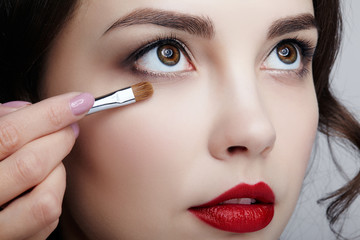 Close up portrait of beautiful young brunette woman face. Female applying mascara to eyelashes