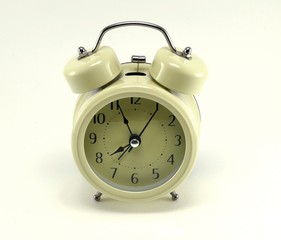 Beige alarm clock, stylized antique with black arrows.