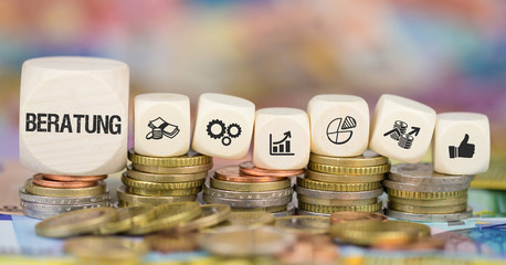 Beratung / Würfel auf Münzenstapel mit Symbole
