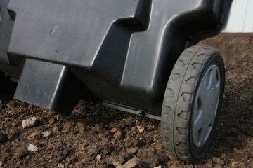 Sowing lawn grass seeds with a drop lawn spreader in the summer garden