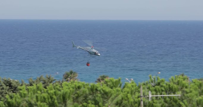 Elicottero antincendio con bambi bucket in volo per spegnere gli incendi nella foresta.