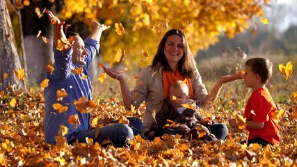 Happy family joy and fun in nature playing with autumn leaves, slow motion