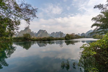 Panoramic view of green mountains reflected in still water. Yangshou, China