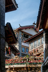 Fototapeta na wymiar Scenic street in the Old Town of Lijiang, Yunnan province, China. Wooden facades of traditional Chinese houses. The Old Town of Lijiang is a popular tourist destination of Asia.