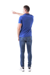 Back view of young man in casual clothes pointing left with right arm finger. Full body isolated on white background. 