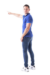 Back view of young adult casual man turning and looking at camera showing directions with hand gesture. Full body isolated on white background. 