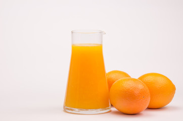 fresh orange juice in a glass bottle with ripe oranges on a white background