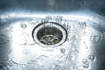 Wasser fliesst im Abluss im Becken