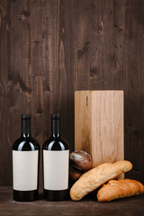 Naklejka premium wine composition with bread, two bottles in box and wineglass on wooden background