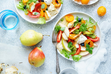 Original panzanella salad with mozarella, toasted baguette, tomatoes and plums on rustic background. Summer cuisine concept. Top view