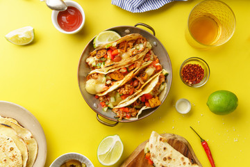 Overhead image of mexican tacos with chili con carnes and grated cheese served over a yellow background