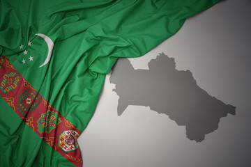 waving colorful national flag and map of turkmenistan.