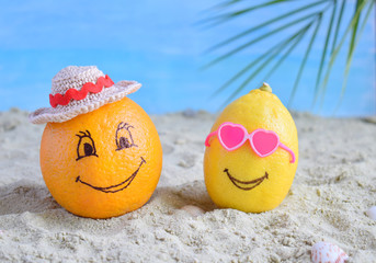Creative minimal summer idea. Citrus hipster. Orange in bamboo hat and lemon in sunglasses on sand. Tropical beach concept. Creative art. Fun party Mood. Copy space