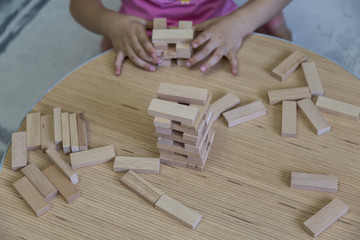 the kid play wooden blocks game , make tower in the preschool.