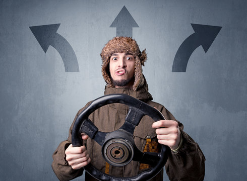 Young Man Holding Black Steering Wheel With Three Arrows Above His Head Pointing In Different Directions