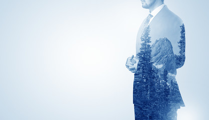 Young businessman standing and meditate with trees on the background 