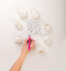 Female hand next to a few crumpled paper balls drawing mixed media icons