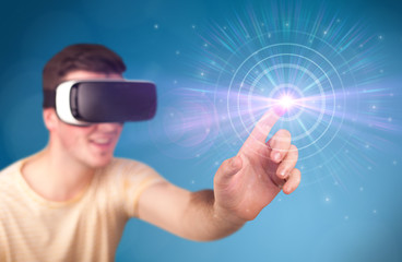 Young impressed man wearing virtual reality goggles with blue circles around his finger 